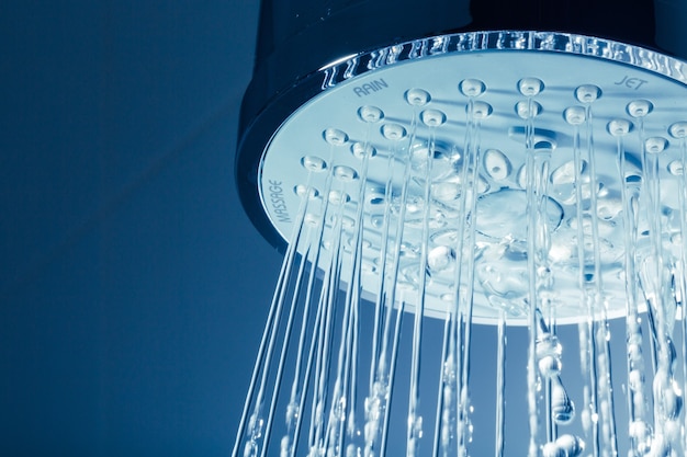 Shower Head with Water Stream on Blue Background