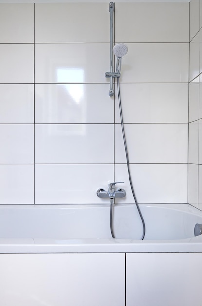 Shower rail in bathtub against white tiles