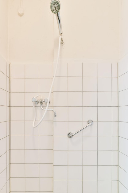 타일로 마감된 흰색 벽이 있는 샤워실 내부