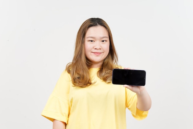 黄色の T シャツを着ている美しいアジアの女性の空白の画面のスマート フォンにアプリや広告を表示