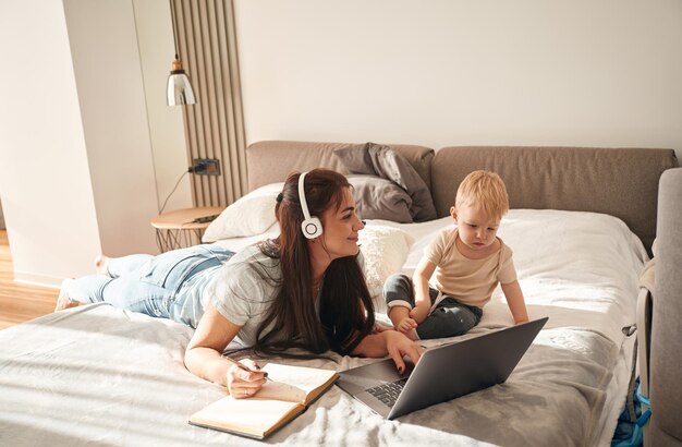showing laptop mother with her little son is at home in domestic room