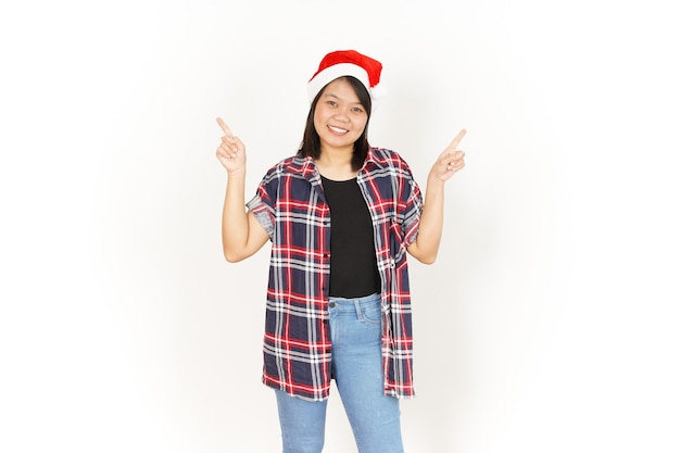 Показывая и указывая вверх продукт красивой азиатской женщины в красной клетчатой рубашке и шляпе Санта-Клауса
