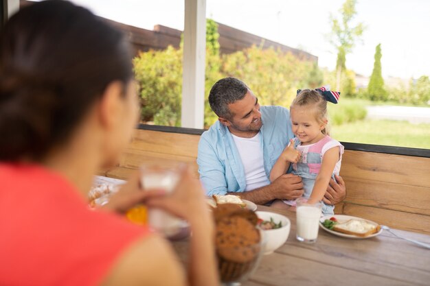 Showing thumb up. Cute blonde daughter showing thumb up feeling excited before breakfast outside