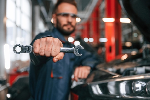 写真 手にあるツールを示す 車の修理工は自動車のガレージにいます