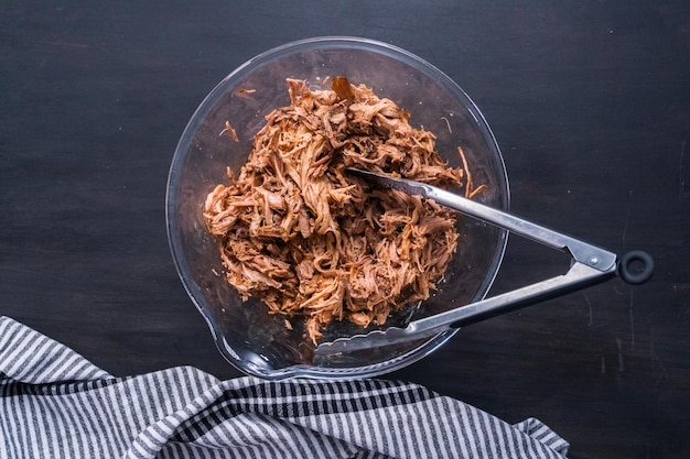 Photo shredded cooked pork in glass bowl.