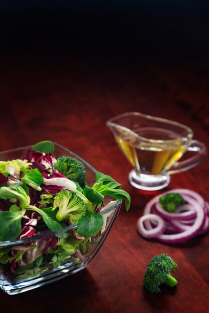 Shredded ingredients for organic salad with broccoli and onion, olive oil in glass bowl