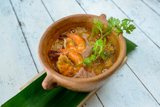 Shrimp broth in clay bowl on white painted wooden table Brazilian food widely consumed on the coast