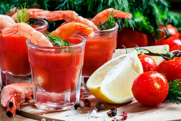 Shrimp cocktail in small glasses cherry tomatoes dill parsley and lemon with salt and spices selective focus