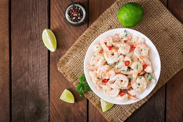 Shrimp in a creamy garlic sauce with parsley and lime in white bowl