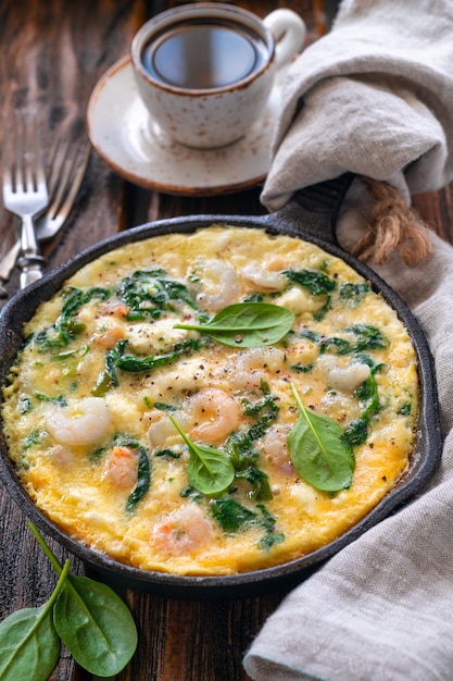 Frittata di gamberetti con spinaci freschi. una grande porzione viene cotta in una padella di ghisa. colazione biologica. stile rustico.