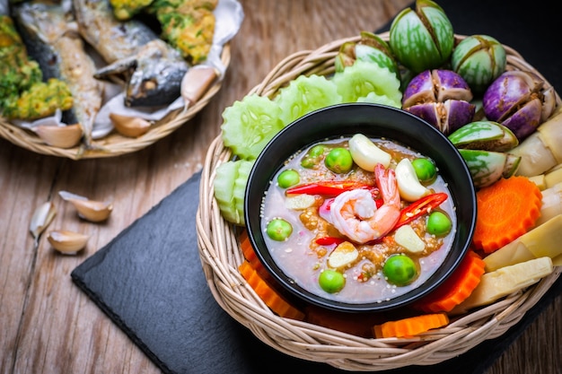 Shrimp - paste sauce with vegetables, omelet, fried mackerel  on wooden table. 