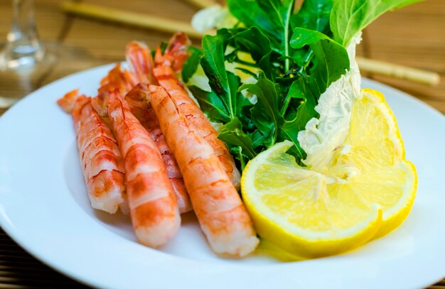 Shrimp on a plate with lemon and salad