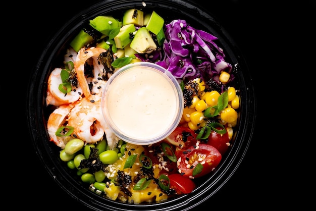 Shrimp poke Bowl with avocado cabbage corn tomato beans View from above Black background Culinary dish for restaurant menu