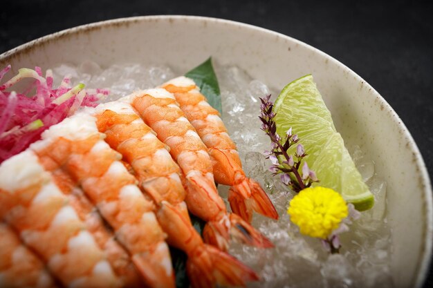 Shrimp sashimi with lime and ice on a bamboo leaf