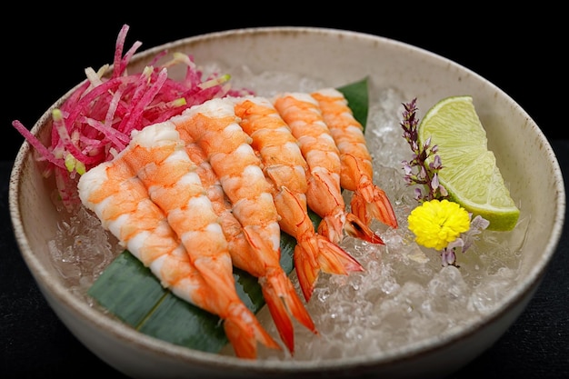 Shrimp sashimi with lime and ice on a bamboo leaf