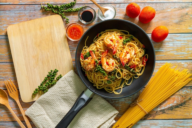 Shrimp SpaghettiStir fry noodles with vegetables and shrimps in black iron pan Slate background