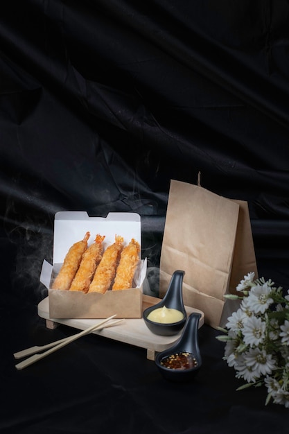 Shrimp tempura in paper packaging, dark background with smoke.