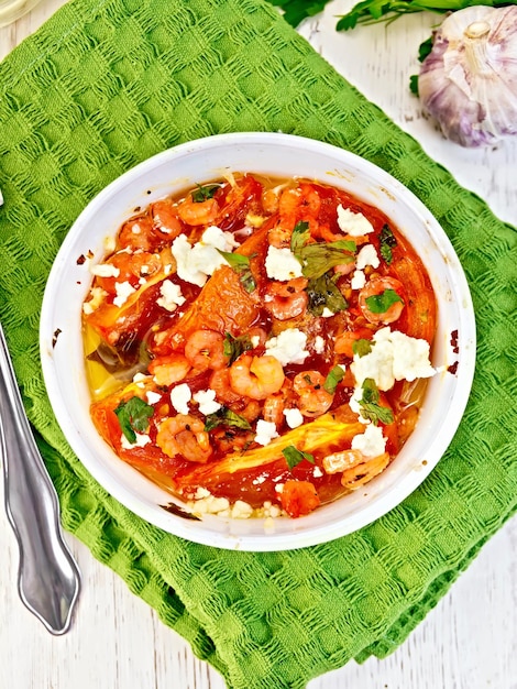 Shrimp and tomatoes with feta in white bowl on napkin top