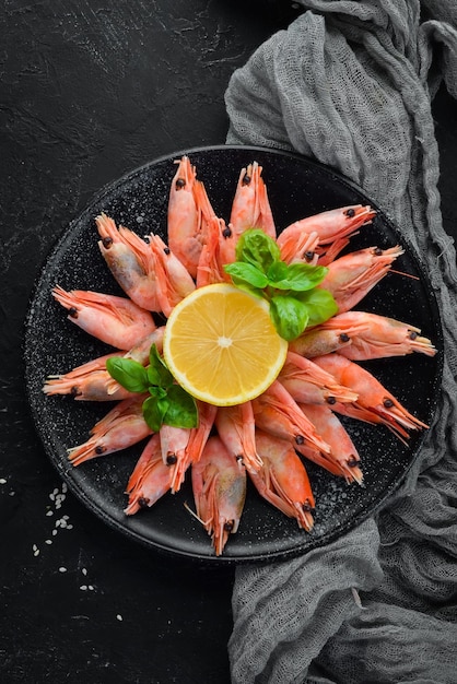 Shrimp with lemon in a plate on a black background Top view Free copy space