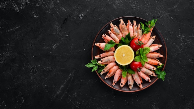 Shrimp with lemon in a plate on a black background Top view Free copy space