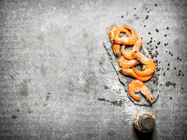 Shrimp with peppercorn and salt on stone table.