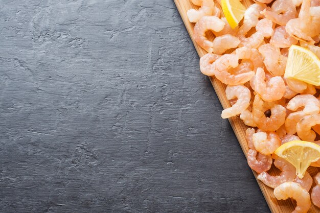 Shrimp with spices and lemon on a wooden Board. Dark background with Copy space