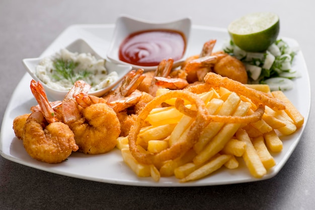 Foto bani di gamberi o gamberi fritti con patatine fritte e salsa di pomodoro serviti in un piatto isolato su sfondo grigio vista dall'alto del cibo arabo