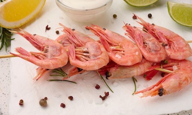 Shrimps strung on wooden sticks soy sauce and spices on a white table top view