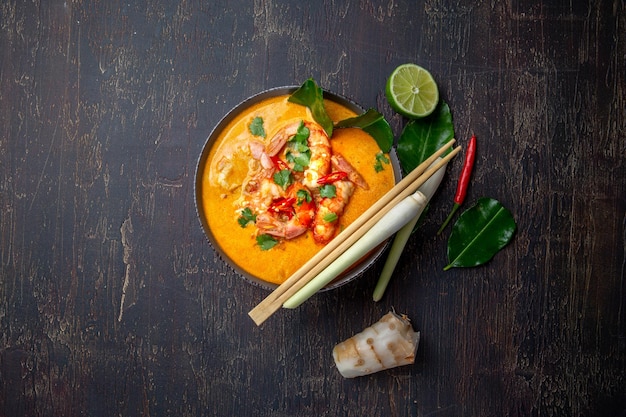 Photo shrimps tom yam kung in grey bowl with thai spices on autentic tray top view wooden background