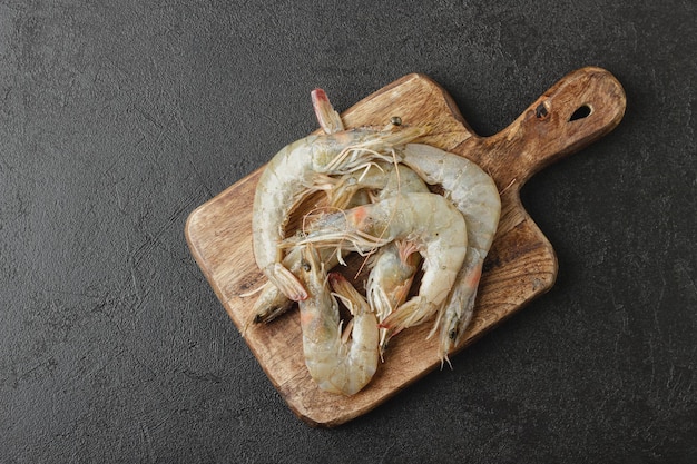 Shrimps on wooden board Raw seafood on dark background Top view of uncooked food with copy space