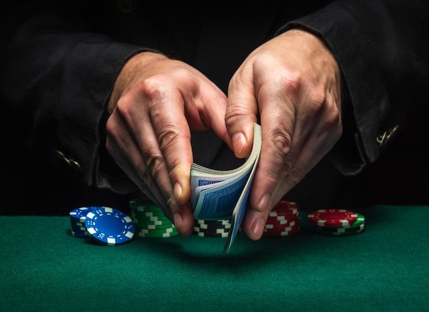 Shuffling of playing cards with the hands of a diler or a croupier in a poker club on a green table