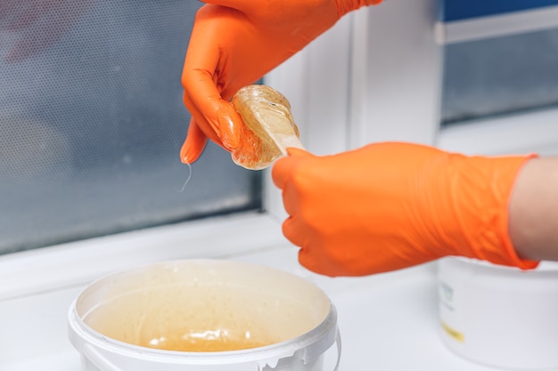 Shugaring master woman stirring sugar paste for hair removal.