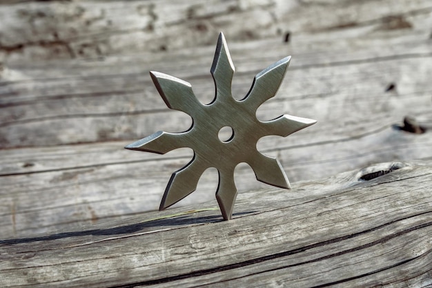 Photo shuriken throwing star traditional japanese ninja cold weapon stuck in wooden background