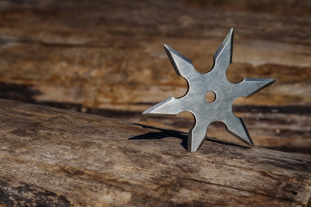 Shuriken throwing star traditional japanese ninja cold weapon stuck in wooden background