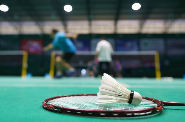 Shuttlecock on green badminton playing court with player in background