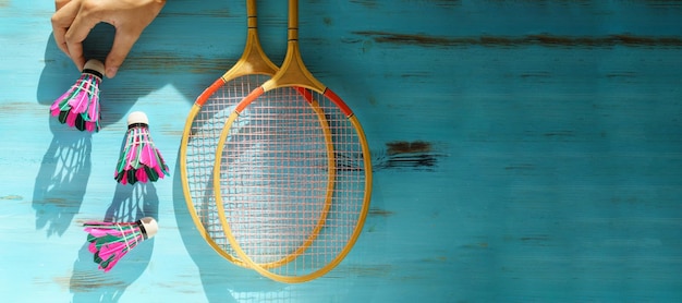 Photo shuttlecocks and badminton rackets on blue wooden background flat lay copy space