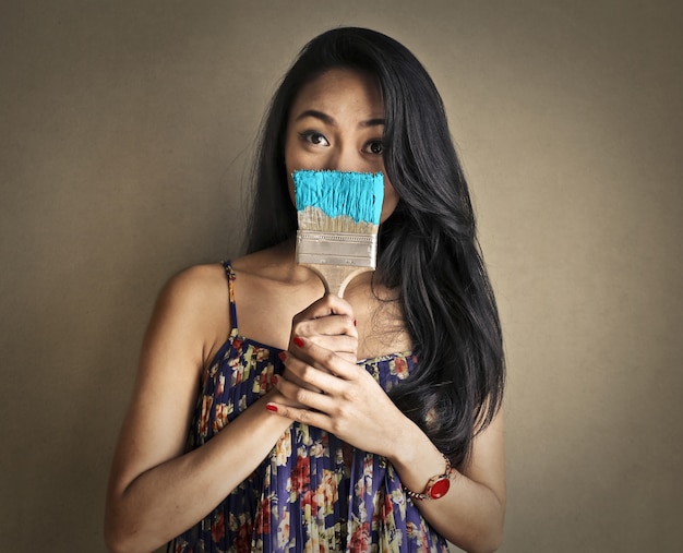 Shy Asian woman with a paintbrush