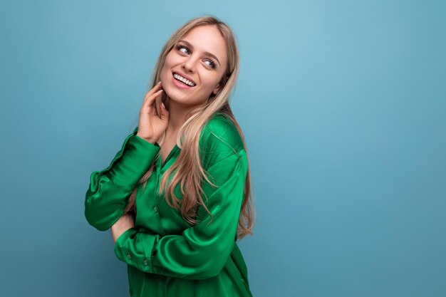 Shy woman in green shirt posing on blue studio background