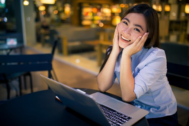 Shy woman using laptop in night time at cafe