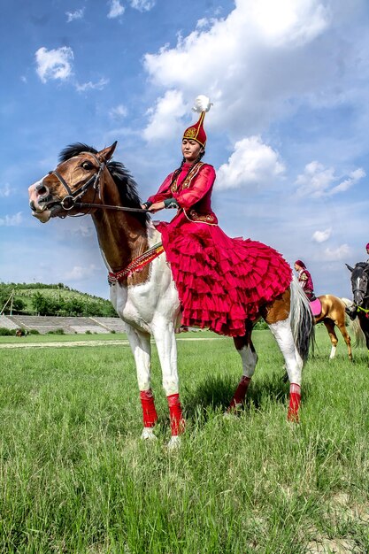 シャムケント, カザフスタン, 2018年5月16日 - イスラム教の聖なる月ラマダンの始まりを記念して市の競馬場で休日民族衣装を着た女の子が馬に乗っています