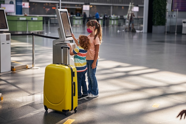 Siblings are using self-service baggage drop machine