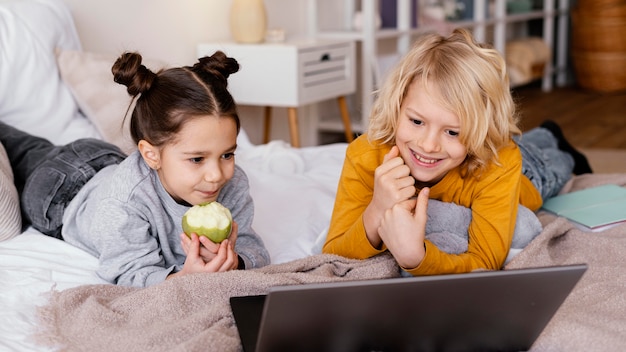 Photo siblings in bed watching video on laptop