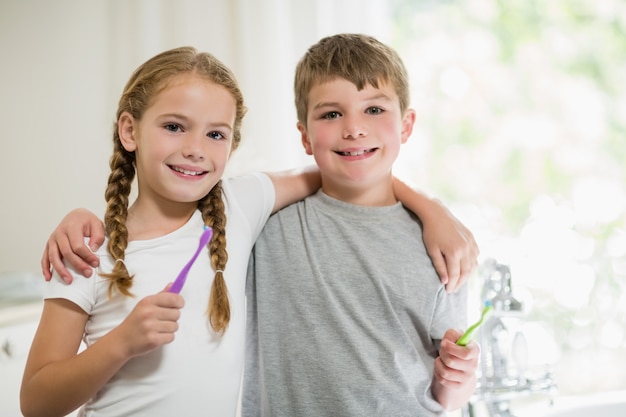 Photo siblings brushing teeth in bathroom