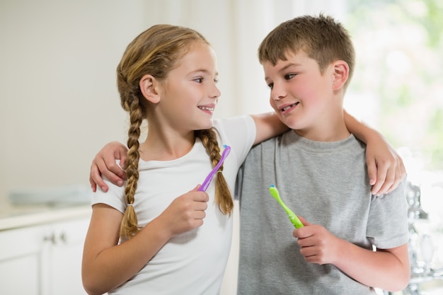 Photo siblings brushing teeth in bathroom