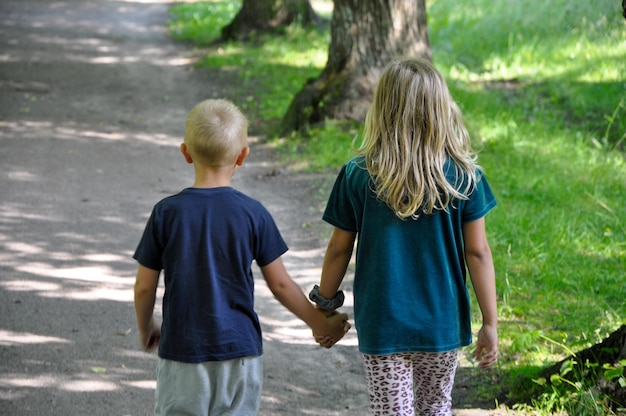 Photo siblings holding hands in the park