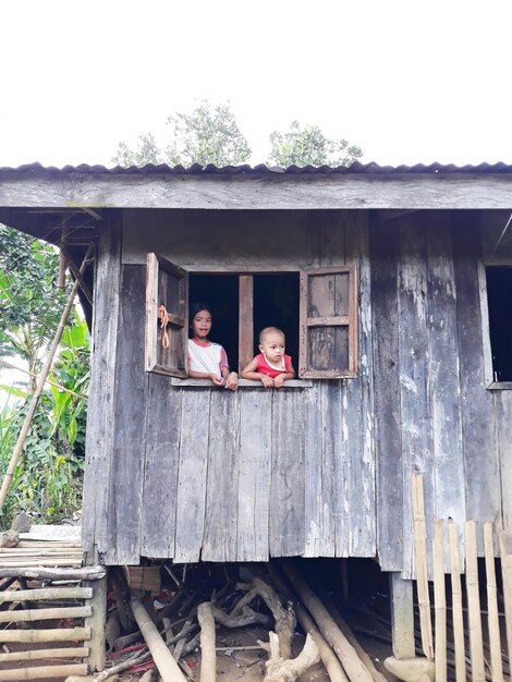 Photo siblings looking through barn window