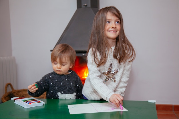 Siblings playing at home with colorful crayons