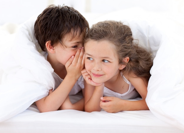 Siblings playing on parent's bed