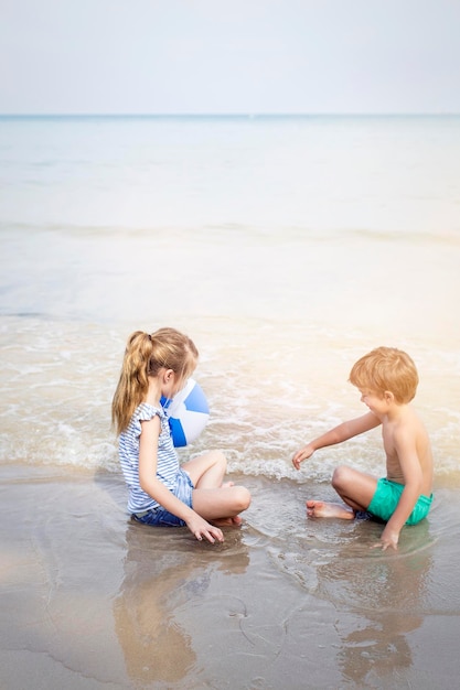 Siblings playing with ball at beach