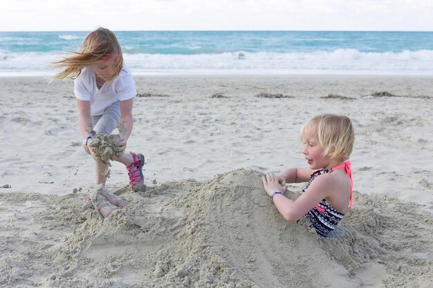 Siblings playing with sand at beach